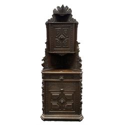 Victorian heavily carved oak corner cupboard, raised shaped back with shelf carved with scrolling foliage, the upper and lower cupboards enclosed by panelled doors with applied mouldings and masks, canted corners with carved leaf and berry decoration 