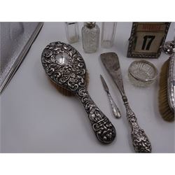 Group of silver, comprising Victorian silver mounted perpetual calendar with various date cards, hallmarked Henry Matthews, Birmingham 1900, silver mounted dressing table items, to include hair brush, with embossed decoration, pair of clothes brushes, and a shoe horn, together with a pair of silver mounted dwarf candlesticks, four cut glass jars/scent bottles with silver covers and a cut glass open salt with silver collar, all hallmarked 