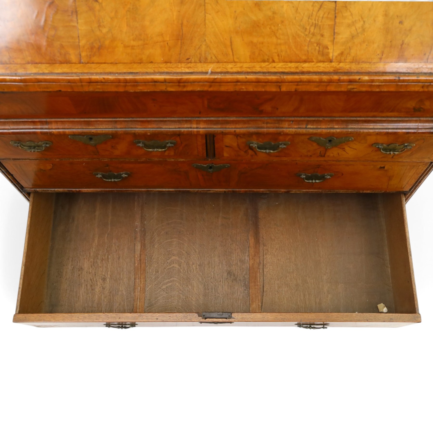 18th century figured walnut bureau, the sloped fall-front enclosing fitted interior with sliding base, pigeon-holes and correspondence drawers with shaped facias, over two short and two long feather-banded drawers with pressed brass handle plates, on bracket feet