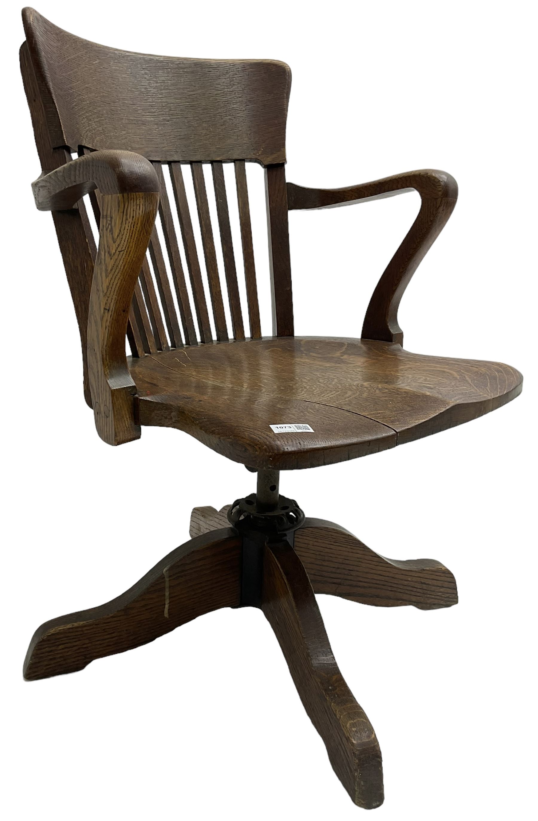 Early 20th century swivel office desk chair, shaped bar back over vertical rails, dished seat, on four splayed supports