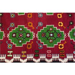 Persian Fars province crimson ground kilim rug, decorated with two rows of geometric emerald green motifs containing stylised plant designs, enclosed by an ivory and dark indigo guard band