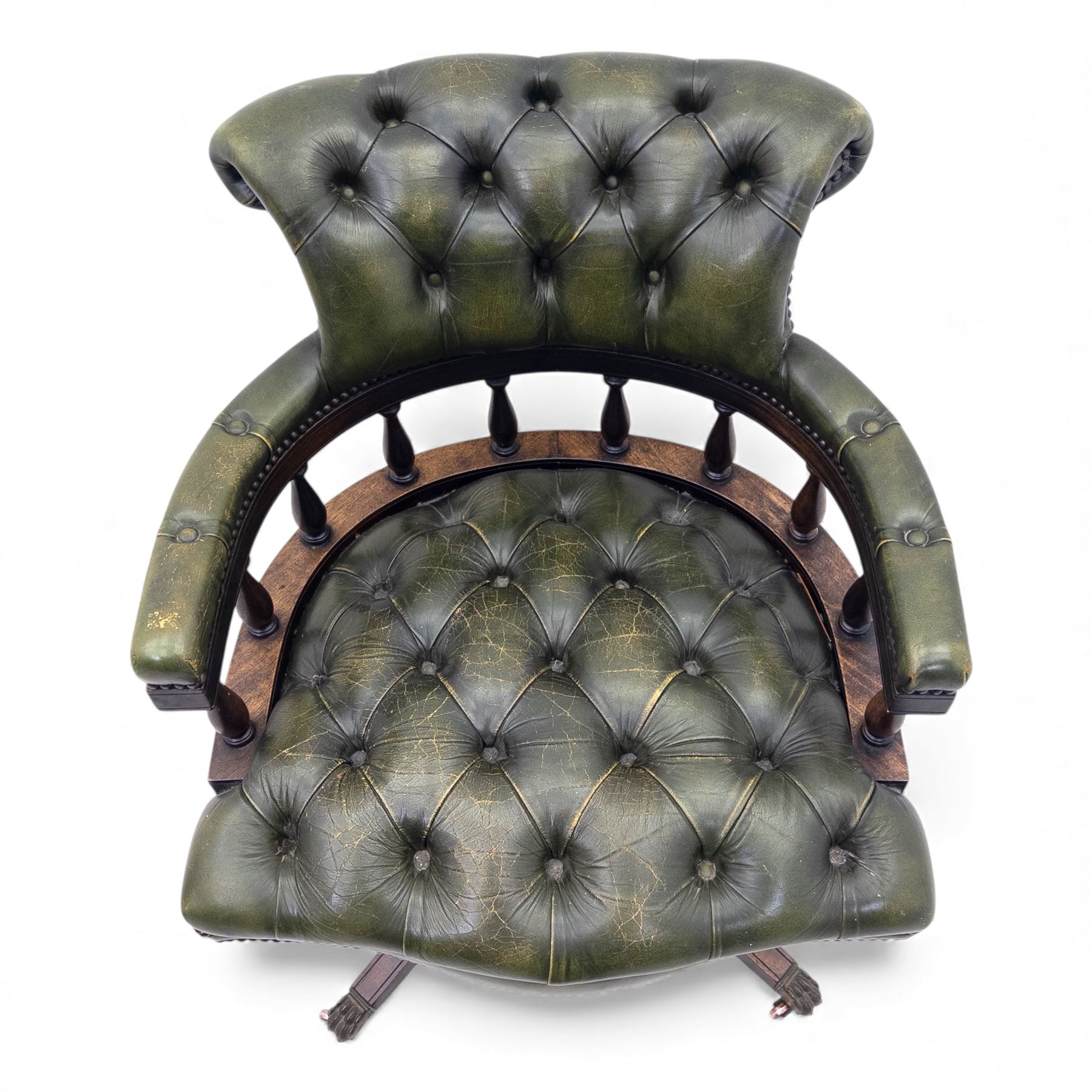 Mid 20th century buttoned green leather office chair, the curved back and arms over a circular frame with turned spindle supports, on a revolving base with four splayed legs and brass castors