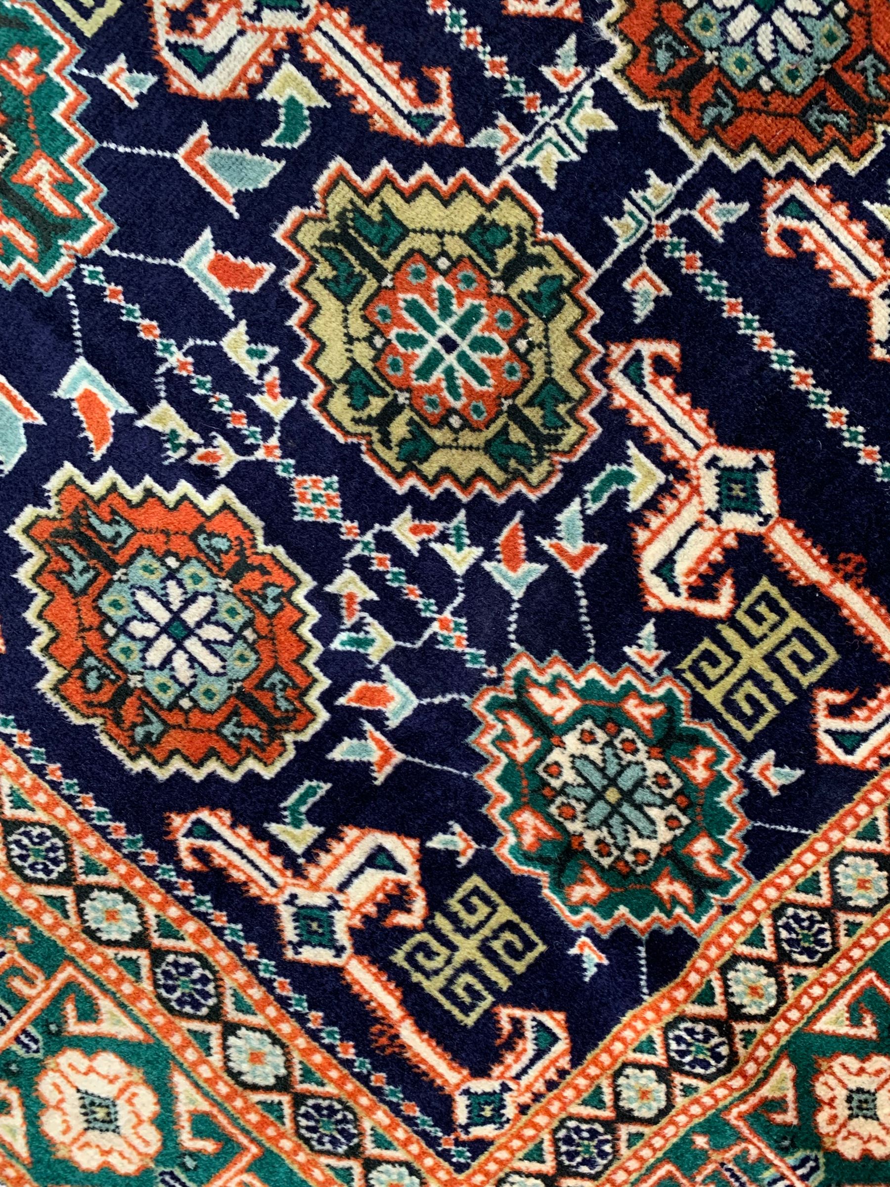 Small Persian indigo ground rug, the field decorated with Gilt motifs with trailing bead and stylised foliage, emerald green ground border decorated with geometric design and flower heads