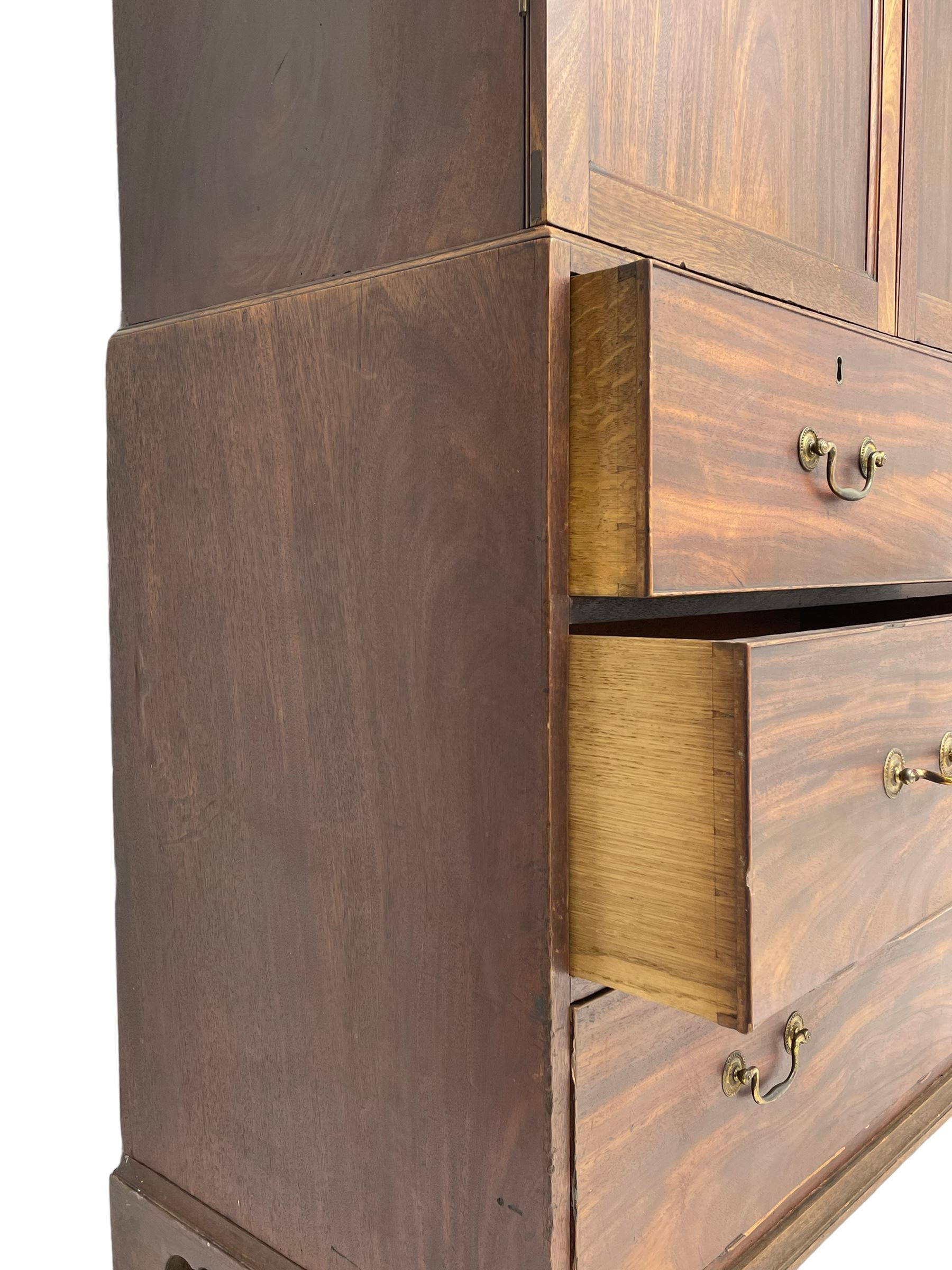 George III mahogany Gentleman's linen press, the projecting cornice over two panelled cupboard doors enclosing three sliding trays, the base fitted with two short over three long graduating cock-beaded drawers, lower moulded edge over bracket feet