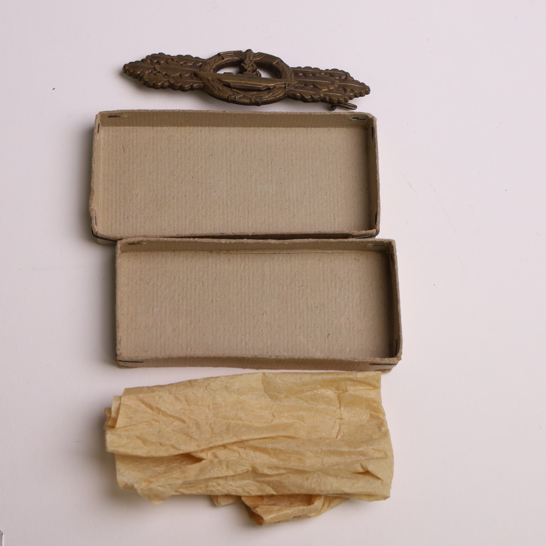 WWII German Kriegsmarine U-Boat combat clasp in bronze by Schwerin Berlin, with the original horizontal pin and catch fixing, makers mark to the reverse “ENTWURF PEEKHAUS AUSF SCHWERIN BERLIN 68” in original packaging