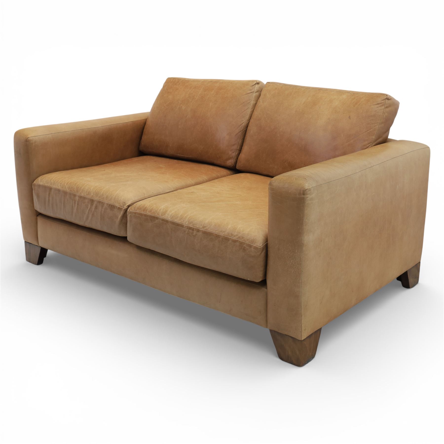 Modern two seat sofa in tanned leather, loose seat and base cushions, block arm rests above dark stained block supports 