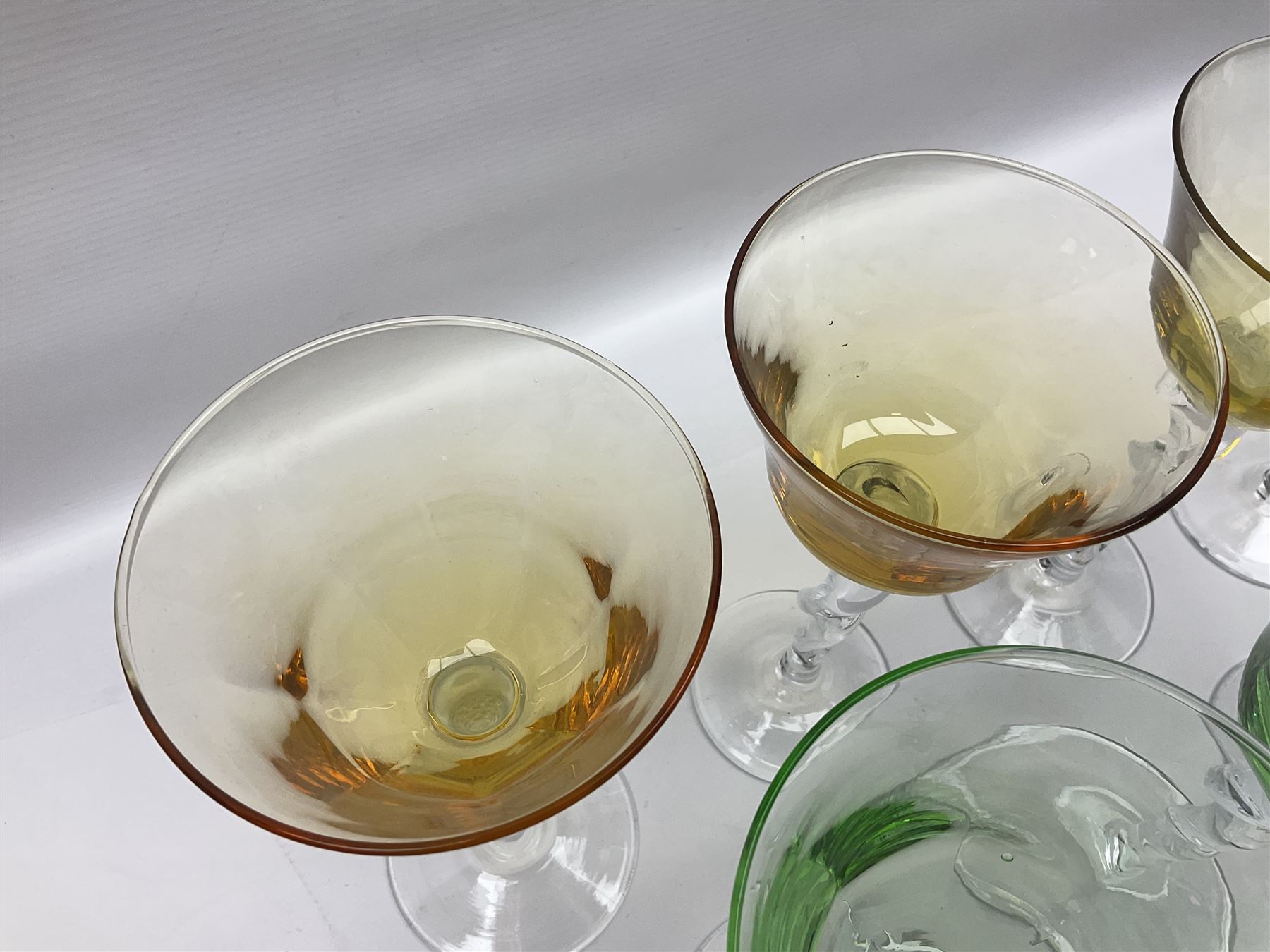 Ten coloured Adriana wine glasses by Abigails, to include blue, green, pink and yellow examples, each with part faceted bowl and twist stems, together with two similar orange examples with pulled stems, H24cm