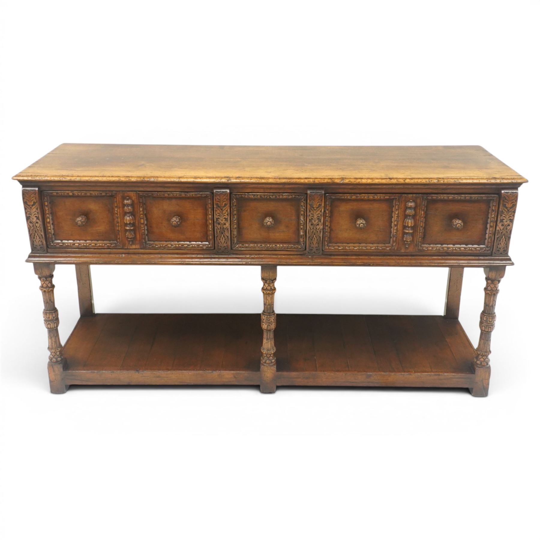 Titchmarsh & Goodwin - Tudor oak dresser base, three drawers flanked by foliate carving and carved wooden knobs, on turned and carved supports, united by a full length undertier