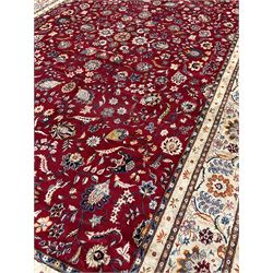Large fine Persian Kashan carpet, the deep red ground field decorated with interlaced foliate and stylised plant motifs, seven band pale ivory ground border, the main band decorated with trailing foliate and flower head motifs of orange and blue