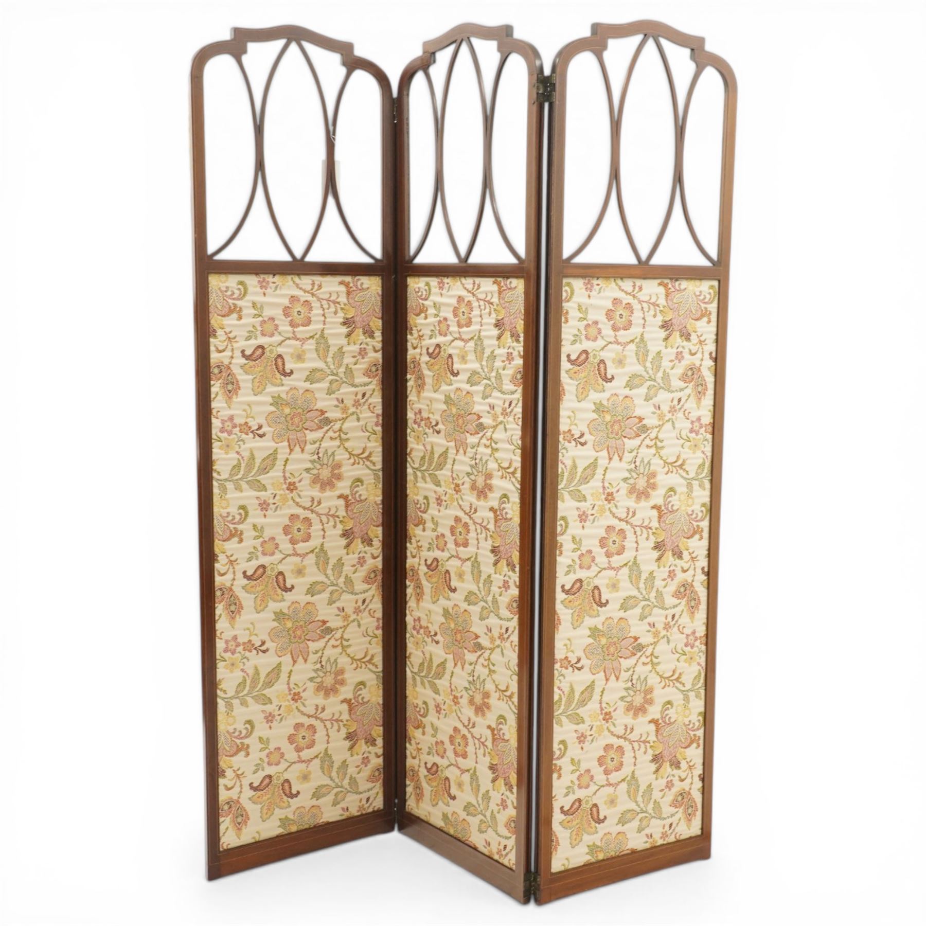 Edwardian inlaid mahogany three-fold screen, each panel with shaped cresting and satinwood line inlaid frame, with intersecting astragal bars, lower panels upholstered in floral fabric, hinged folding action on brass hinges
