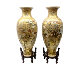  Pair Japanese Satsuma floor vases, Meiji Period, ovoid form, decorated with enamels and gilt, each with four panels depicting a scene of a Daimyo Procession, Samurai in full armor and female figures in an interior setting, on grounds of scrolls and geometric designs with hardwood stands, red painted signature to base, H76cm of vases  