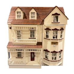Horse Shoe Cottage - scratch-built wooden doll's house as a three-storey double fronted cottage painted in white and maroon; double hinged front elevation with veranda, balcony and bay windows opening to reveal four rooms including fitted kitchen and bathroom; under a simulated tiled pitched roof with dormer windows hinged along the ridge containing two attic bedrooms; fully furnished including window seats plus numerous accessories and wired for electric lighting L55cm H62cm D42cm