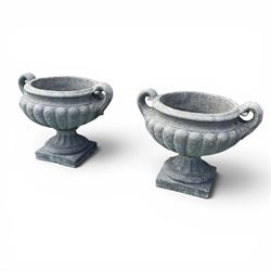 Pair of squat cast stone garden urns of kylix form, gadrooned body with twin pierced scrolling handles, fluted socle on square base