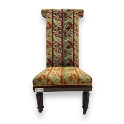 19th century mahogany framed prie-dieu chair, upholstered in red and green patterned fabric, high back with rolled top, standing on turned front supports with castors