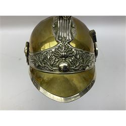 Early 20th century French mounted gendarme's helmet, brass with nickel-silver mountings, broad band embossed with fused grenade, high comb with the face of the gorgon Medusa at the peak and with a black horse hair crest, plume socket at the left, leather-backed nickel-silver chin scales with lion mask mounts.