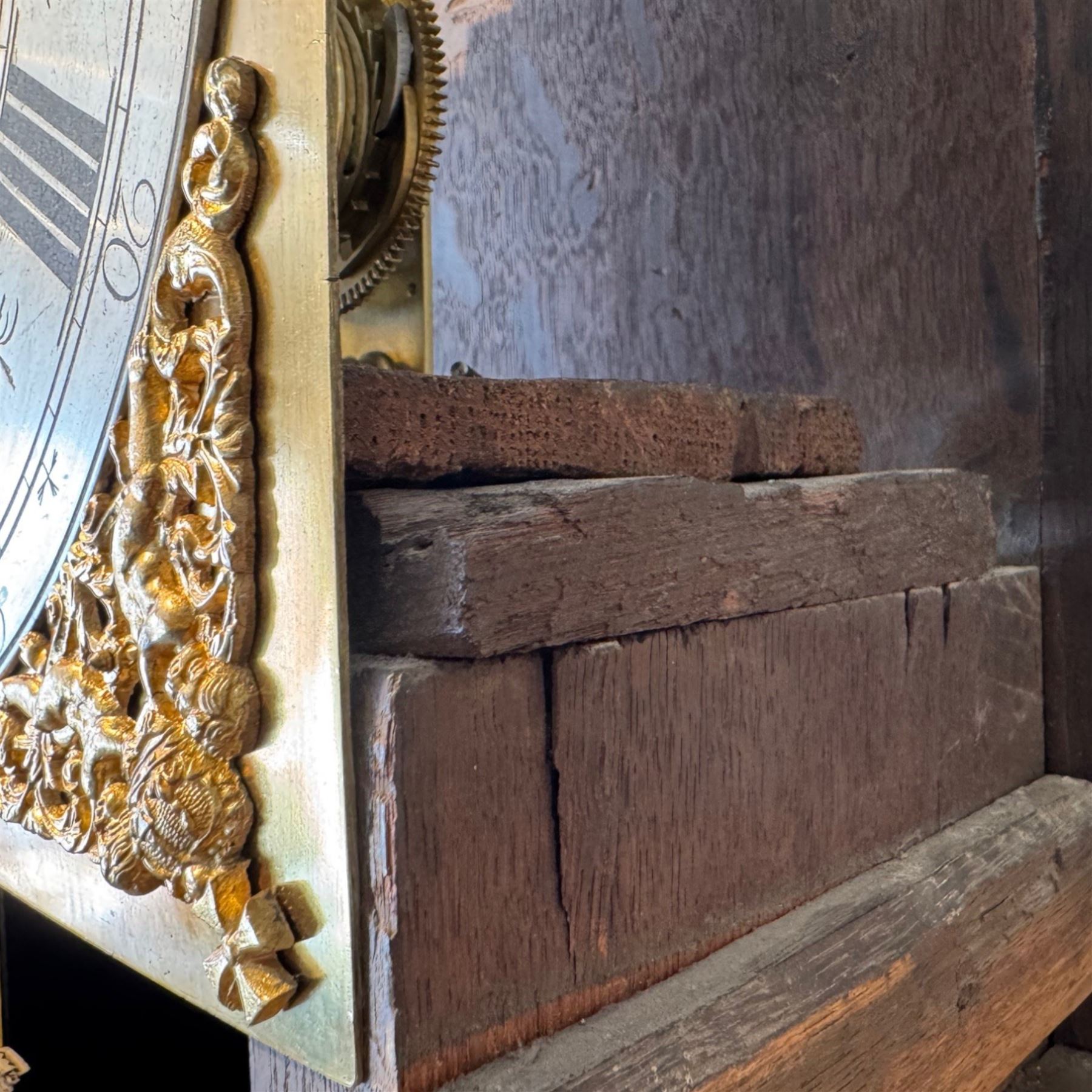 Henry De La Feuille of London-early 18th century marquetry 8-day longcase clock c 1720, hood with a moulded upstand to the domed caddy top, set on a lower upstand above a wide cornice with a marquetry frieze beneath, square hood door with marquetry inlay and attached three-quarter columns with wooden capitals, hood sides with glazed panels, trunk and door inlaid with figural marquetry with various representations of people, birds, scrollwork and foliage, full length door with cock-beading surround and a circular glazed lenticle, the case sides veneered with bordered panels within crossbanded surrounds, plinth with a convex moulding and shallow moulded skirt, brass dial with a matted centre and ringed winding holes, date aperture and seconds dial, silvered chapter with Roman numerals, five minute Arabic’s, minute and inner quarter hour tracks and half-our markers, with pierced steel hands and matching cast scroll spandrels depicting angels supporting a crown, dial pinned directly to a four pillar movement with an outside countwheel and recoil anchor escapement, striking the hours on a cast and polished bell.
With weights, pendulum and key.

Henry De La Feuille was a French Huguenot, born in 1670, moving to Jersey c1690 and finally London where he is thought to have died c1730.
