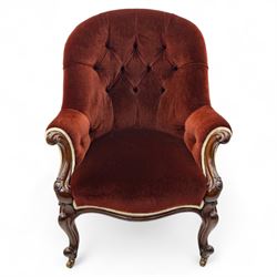 Victorian mahogany framed crimson velvet upholstered tub armchair, with buttoned back and scroll carved arms above a serpentine fronted seat rail, raised upon scroll carved cabriole front legs and plain curved back legs with brass castors 