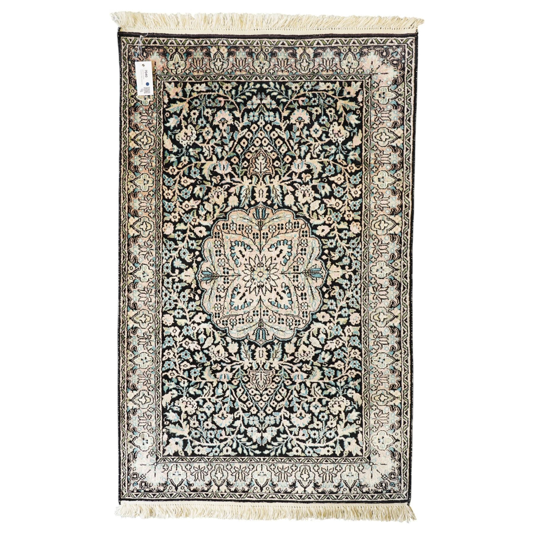 Persian style rug, central floral medallion surrounded by intricate palmetters, vines and rosettes, navy blue ground with ivory and pink highlights