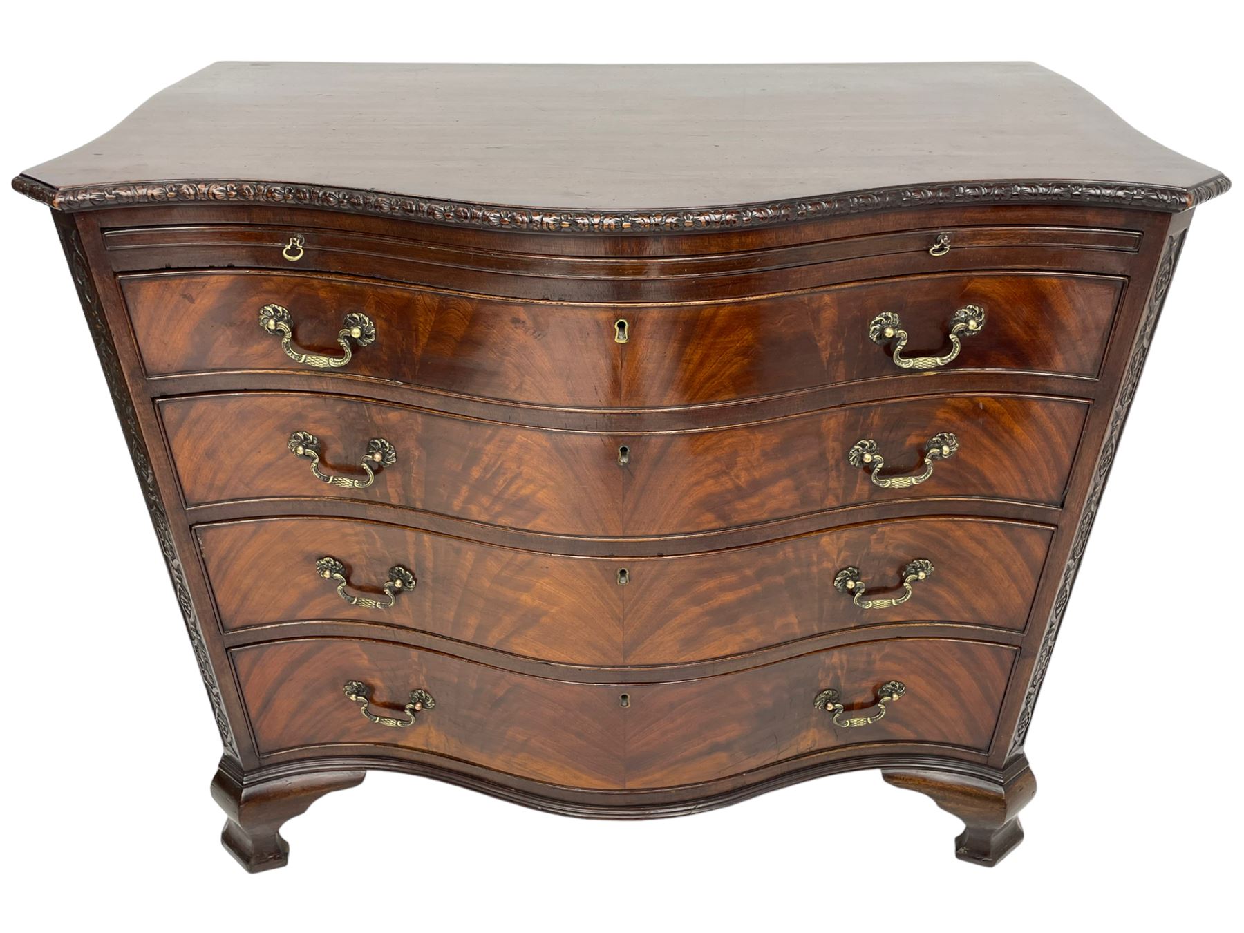 Chippendale design serpentine chest, shaped moulded top carved with repeating flower head motifs, fitted with brushing slide over four graduating drawers, pierced and foliate moulded handle plates with scrolled swan neck handles, canted upright corners carved with flower heads and strapwork, on canted ogee bracket feet