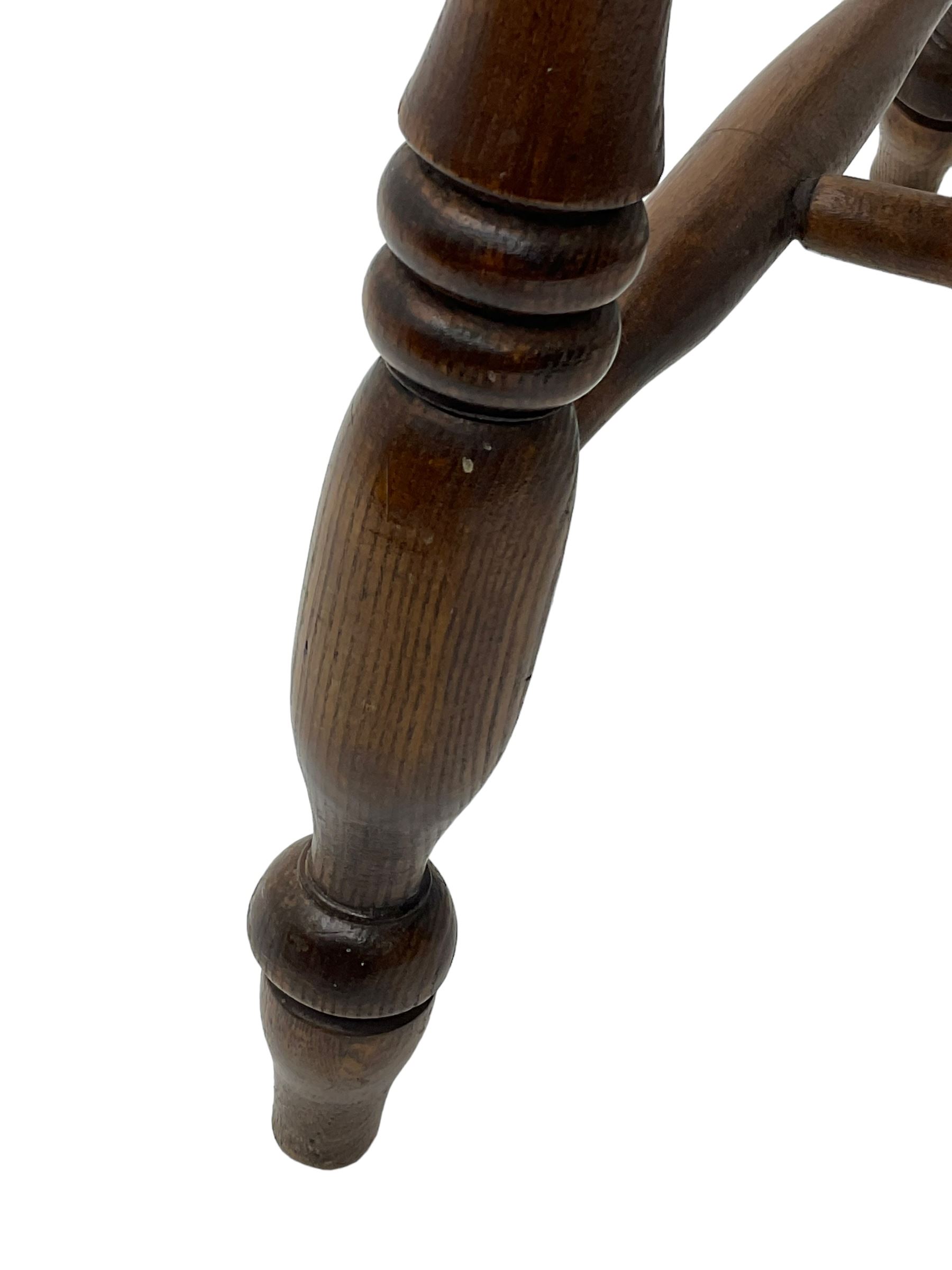 Early 19th century elm farmhouse armchair, the shaped eared cresting rail over tall spindle back, dished seat on turned supports united by H stretchers