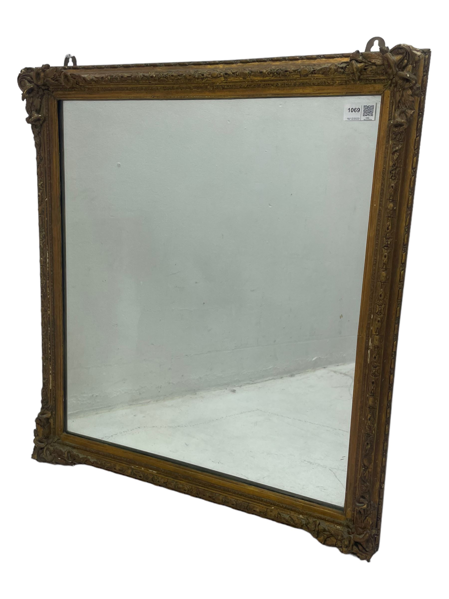 19th century gilt framed wall mirror, the corners decorated with flower heads with extending foliage, plain mirror plate