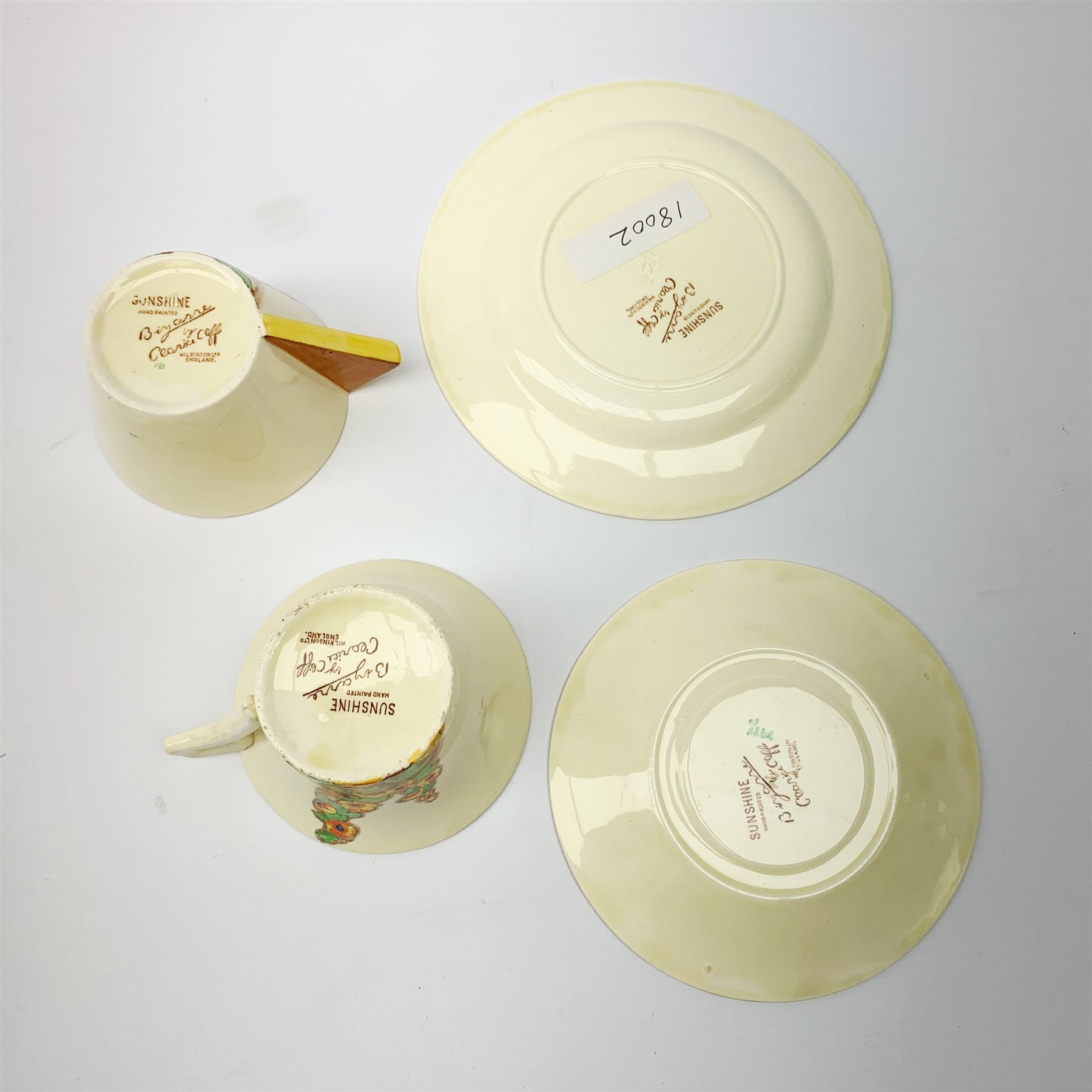 A Clarice Cliff Bizarre by Wilkinson Limited dinner plate, trio and cup in the Sunshine pattern. (5).