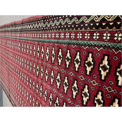 Persian red ground rug, decorated with multiple stylised lozenge motifs. five band border with geometric design