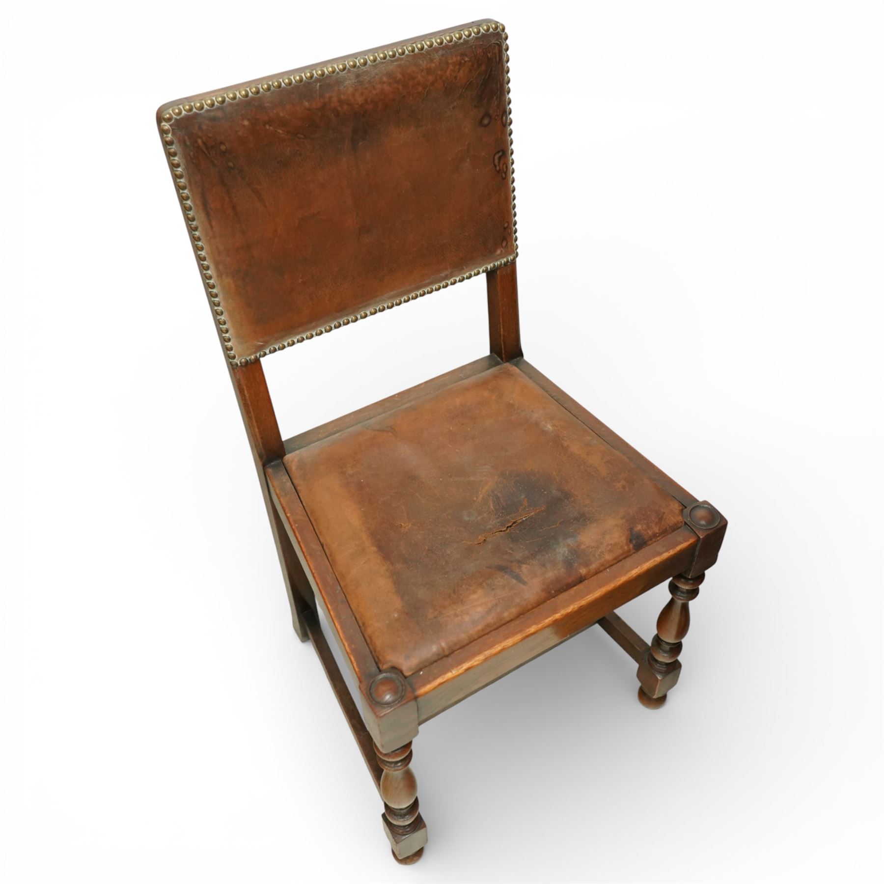 Early 20th century four oak side chairs, with studded leather upholstered backs and seats, on square section legs with baluster turned front supports and straight stretchers