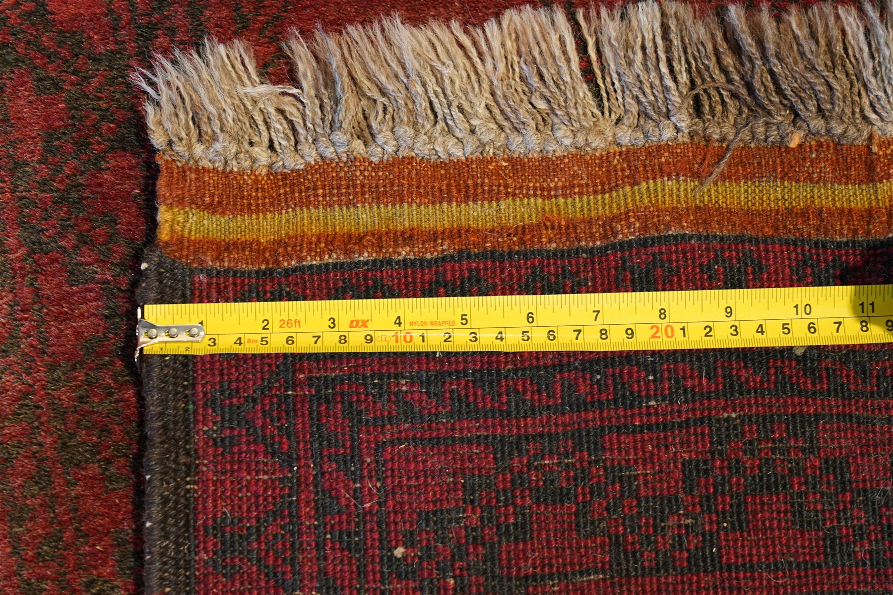 Antique Persian Bokhara red ground runner rug, repeating Gul pattern, surrounded by borders, with fringed ends