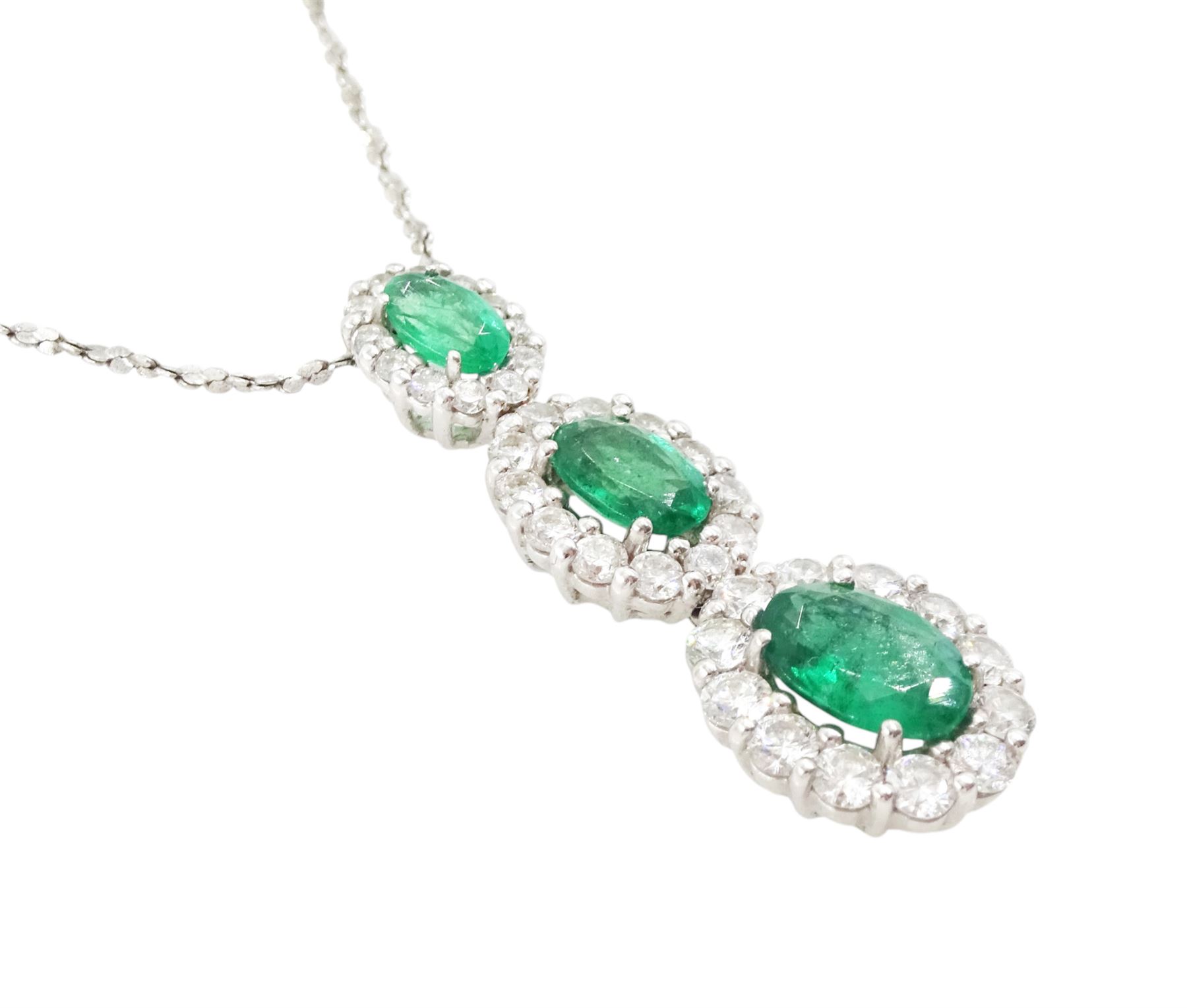 18ct white gold emerald and diamond cluster pendant, three graduating oval cut emeralds, each surrounded by round brilliant cut diamonds, Birmingham 2010, on a fine silver chain, total emerald weight approx 1.05 carat, total diamond weight approx 0.55 carat