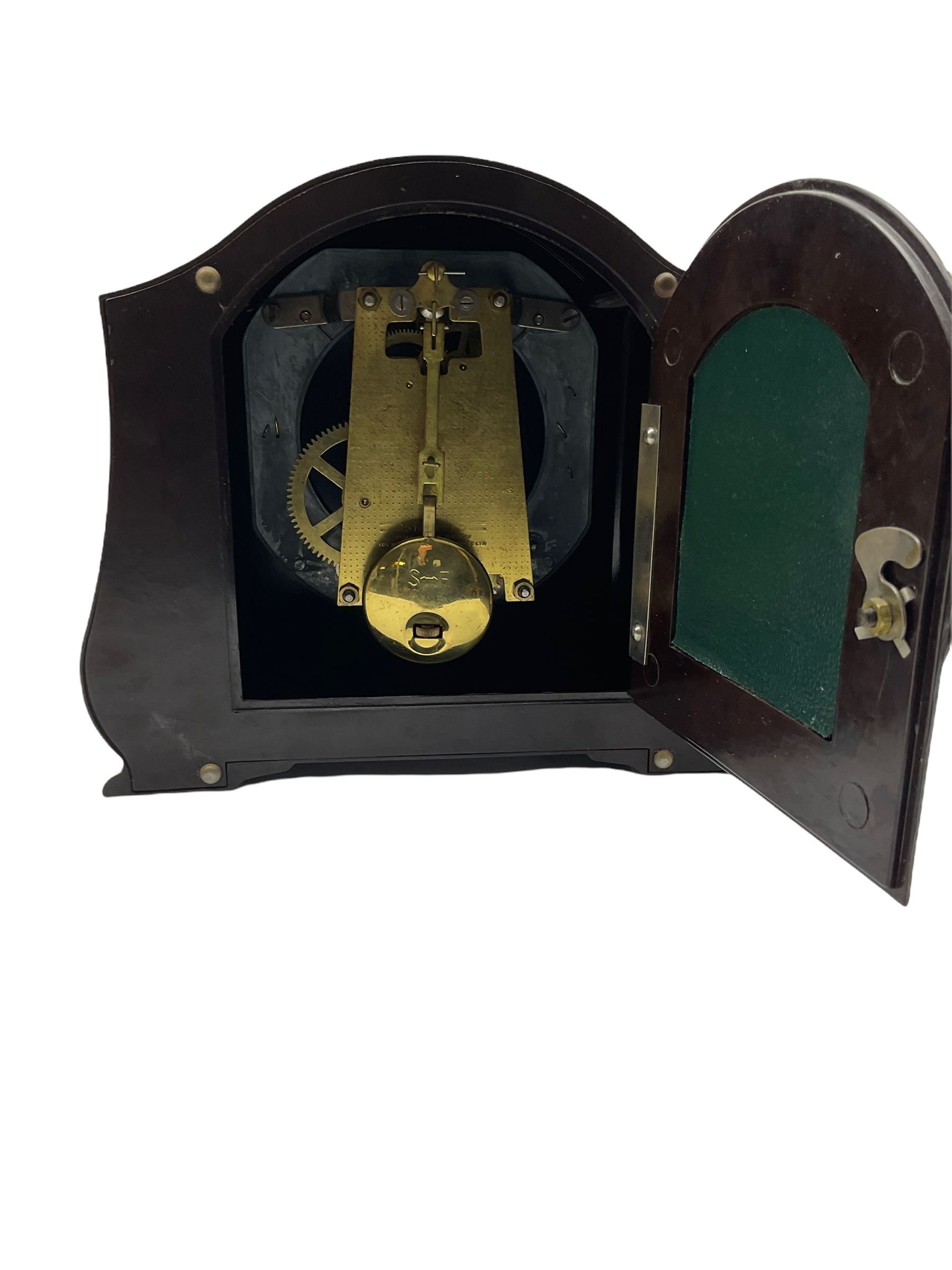 A Retro Art-Deco 1950's Bakelite cased mantel clock with a Smiths timepiece movement housed in a domed top case with curved sides on raised feet, dial with a cream chapter ring, upright Arabic numerals and minute markers, inscribed “Smiths, Made in Great Britain”, dial enclosed within a spun brass bezel and a convex glass, gilt pierced hands, spring driven 8-day pendulum movement. 
With pendulum.
