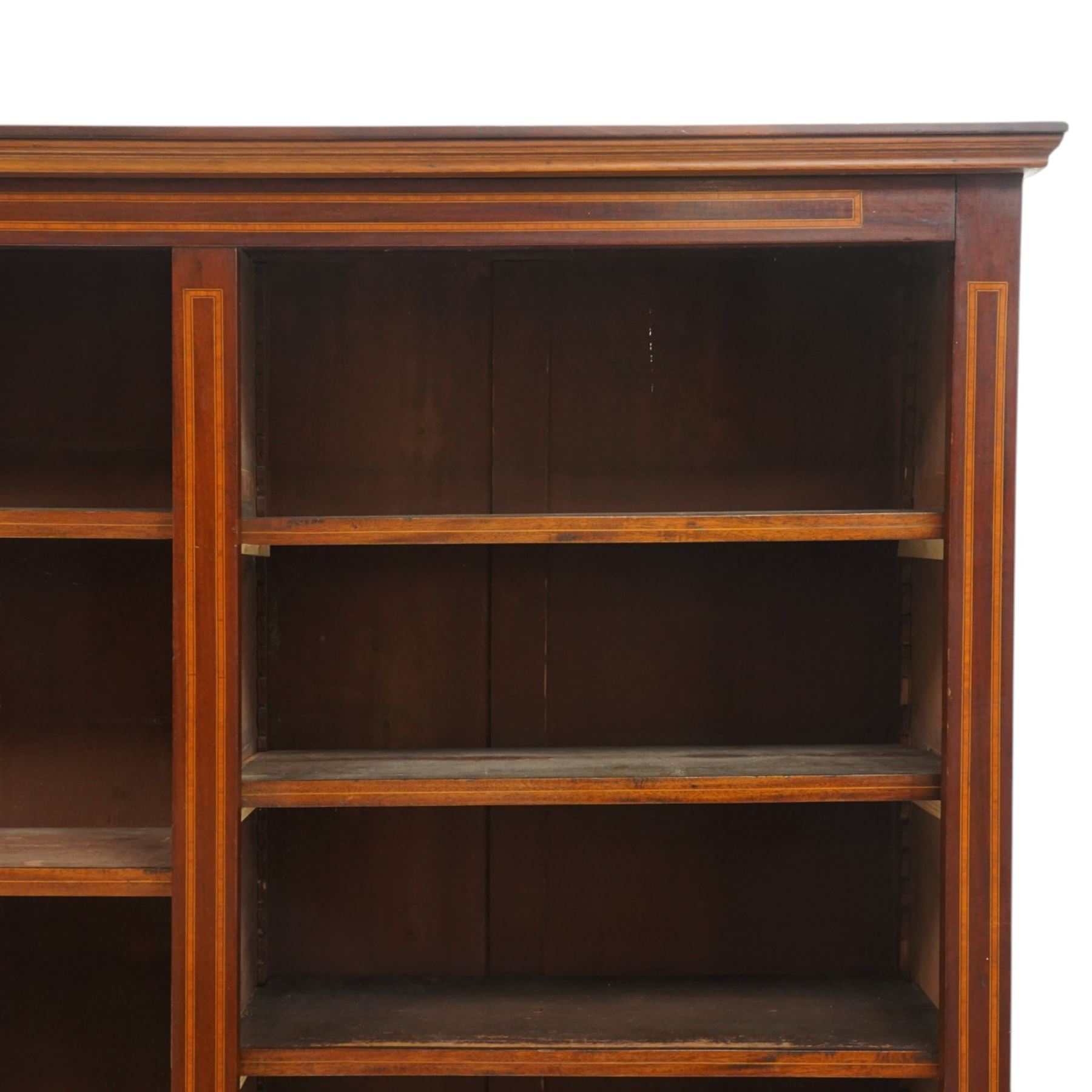 Quality Edwardian inlaid mahogany triple-column open bookcase, projecting cornice over a satinwood banded frieze, fitted with fourteen adjustable shelves with strung facias, the shaped apron on bracket feet