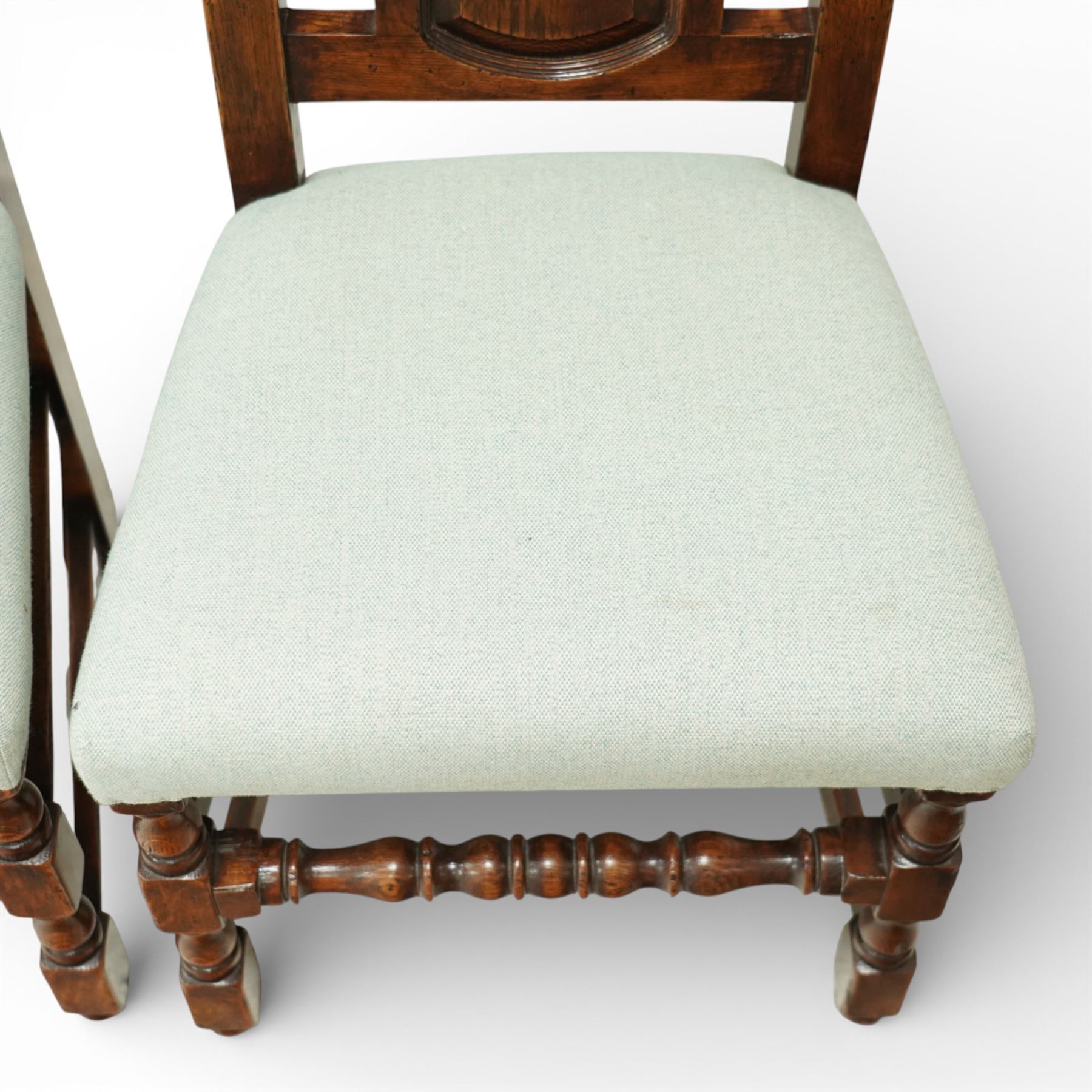 Country House oak high back dining chairs, set of ten comprising eight side chairs and two carvers, each with arched top rail flanked by turned finials over a central fielded panel back, with overstuffed seats upholstered in pale fabric, raised on turned front supports united by stretchers