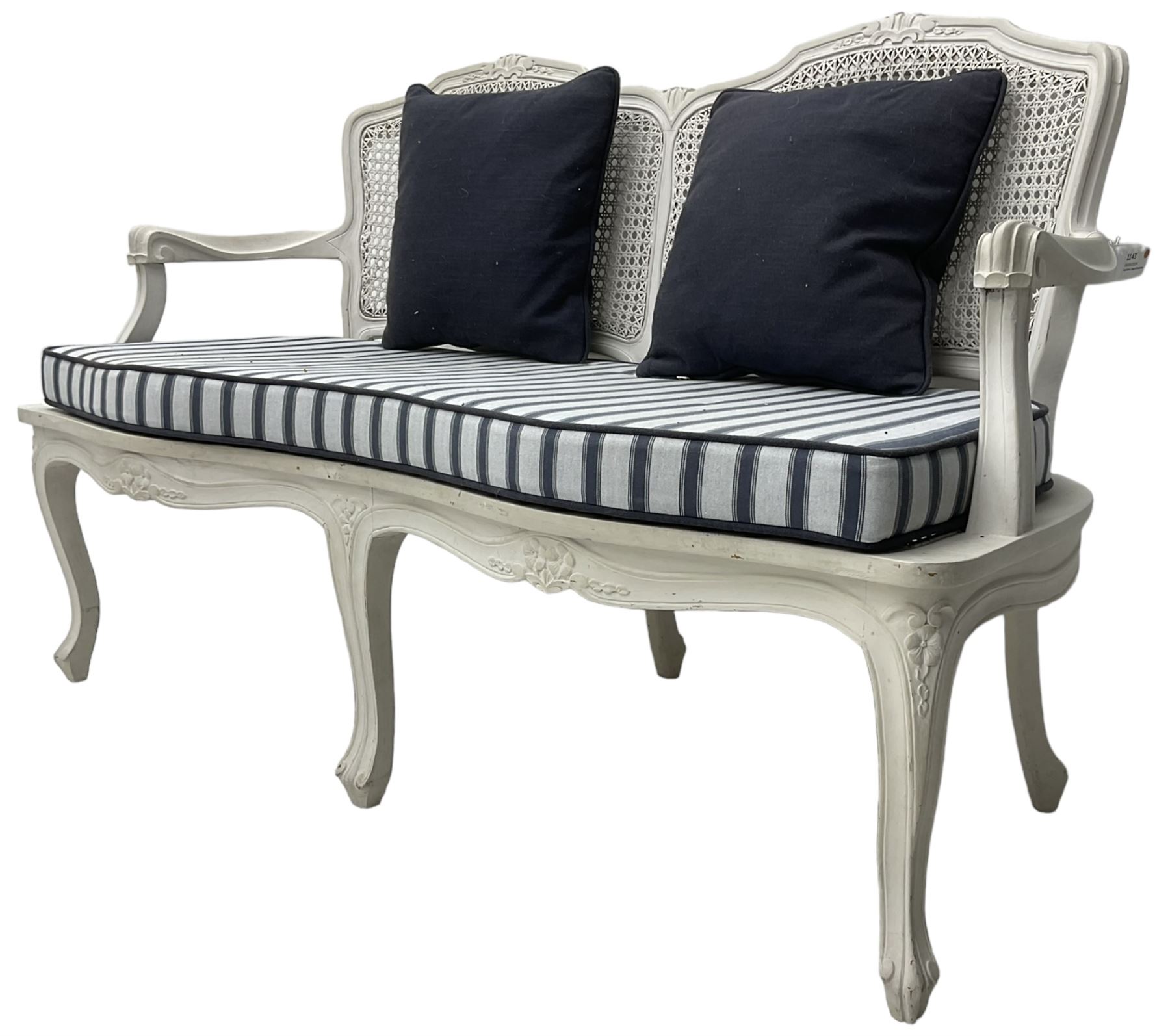French design white painted two seat serpentine settee, floral carved cresting rail over cane back, loose striped upholstered seat cushion, on cabriole supports