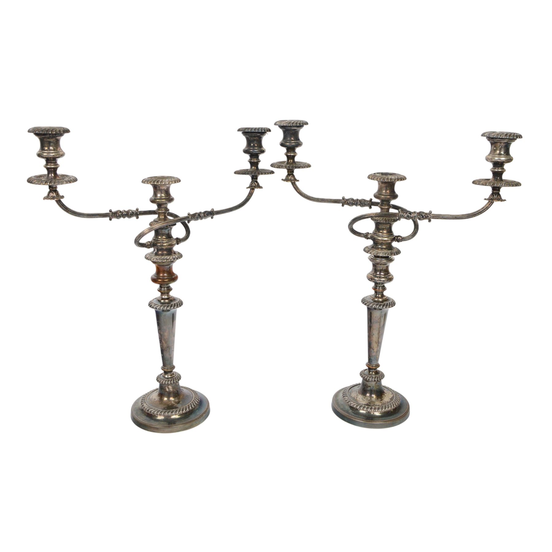 Pair of silver plated three branch candelabra, each with three urn-shaped sconces, with scroll arms, tapering stem upon a circular base, together with silver plated wine flagon