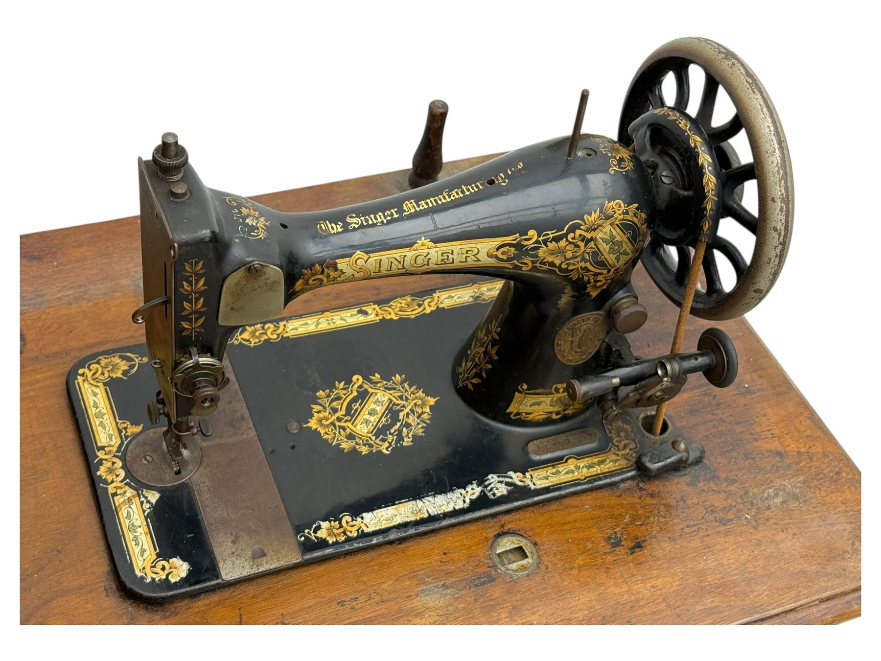 Singer - early 20th century cast iron treadle sewing machine, with hand crank wheel and oak work surface, the machine decorated with gilt foliate detail, complete with rectangular wooden cover and folding extension leaf