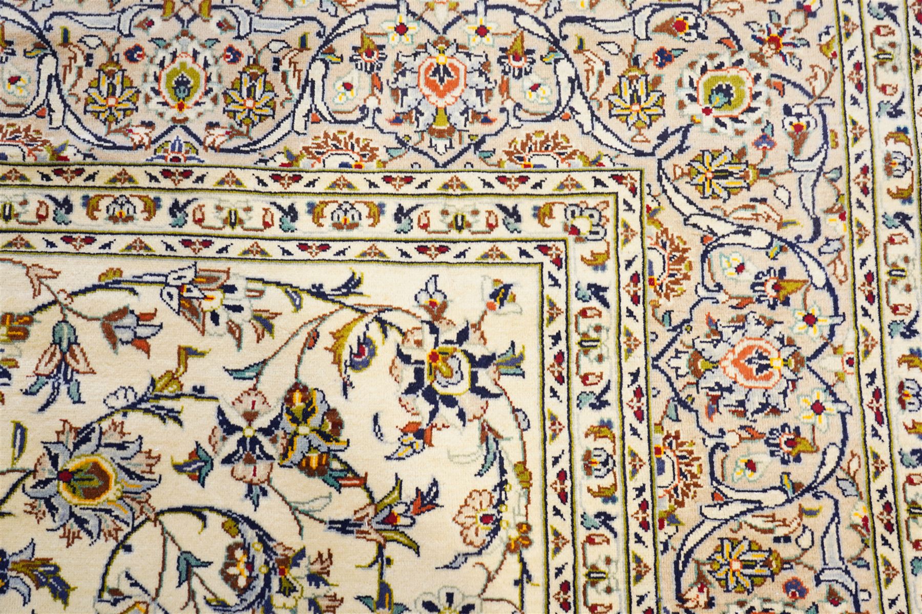Central Persian Kashan hand-knotted carpet, ivory field decorated with an all-over scrolling floral vine design incorporating stylized palmettes, rosettes, and foliate sprays in the Shah-Abassi style enclosed by a series of floral vine borders and multiple narrow guard stripes, cotton fringe ends 