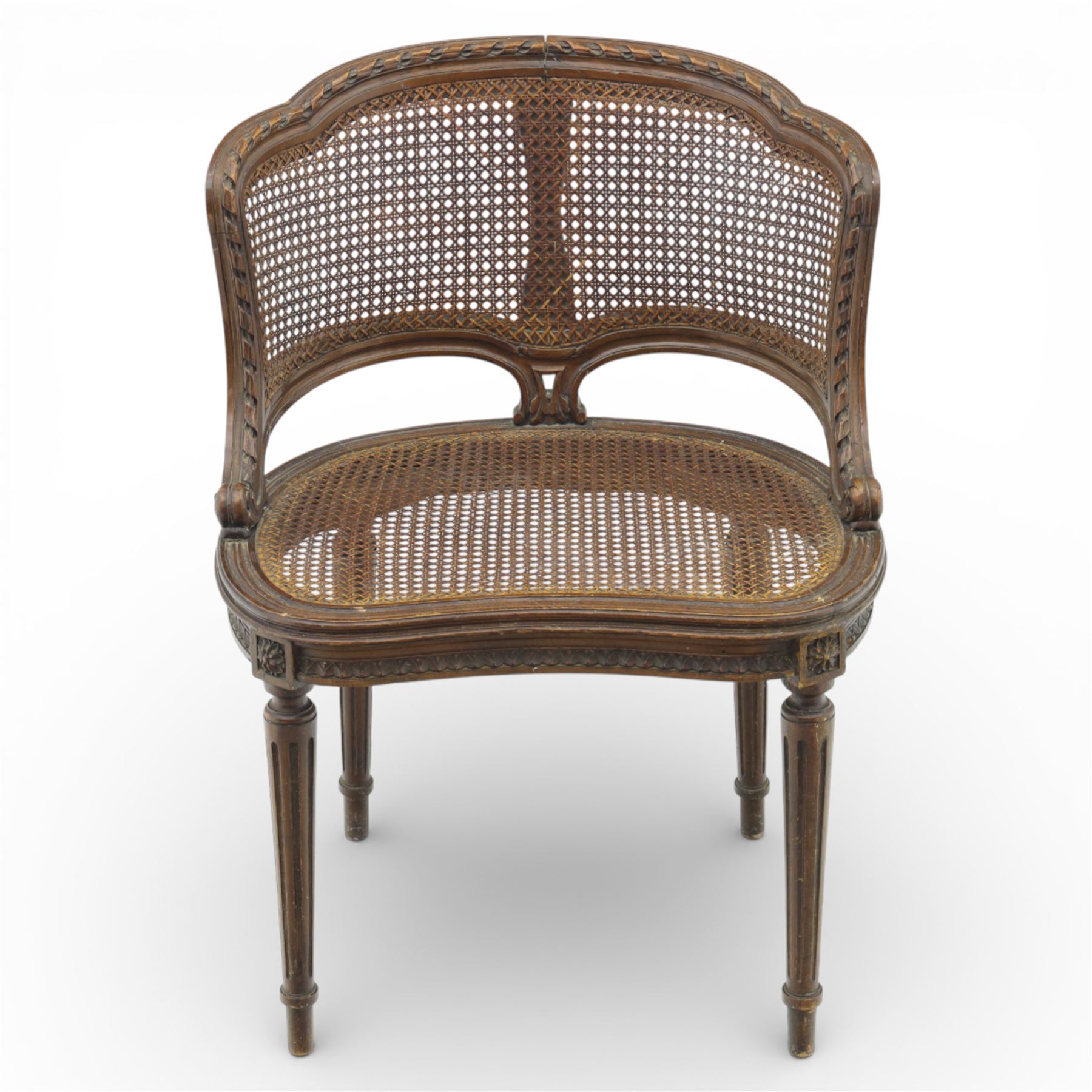 Late 19th century cane bergère armchair, the serpentine shaped back flowing into enclosed arms, the back and seat caned throughout, with carved detail to the crest and arm terminals, on turned legs