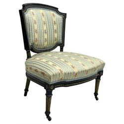 19th century French ebonised low chair, upholstered in floral striped fabric within a moulded frame with gilt line and foliate decoration, the seat of serpentine form, raised on turned fluted legs with toupie feet