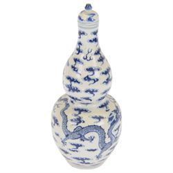 Chinese Kangxi style double-gourd form vase, the blue and white vase surmounted by a domed cover, decorated with dragons chasing a flaming pearl, four-character mark to beneath, H31cm