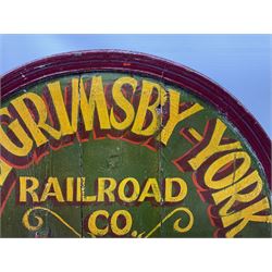 `The Grimsby-York Railroad Co.` painted wooden railway advertising sign 20th century, of planked construction with arched top and moulded border, decorated with an applied wood and metal image of an early steam locomotive in relief, the surrounding wording reading `The Grimsby-York Railroad Co., Fast Dispatch by Rail from Fish Curing Houses of Grimsby & Hull, Est. 1873, Daily Connections to Billingsgate`, 89 x 71cm
