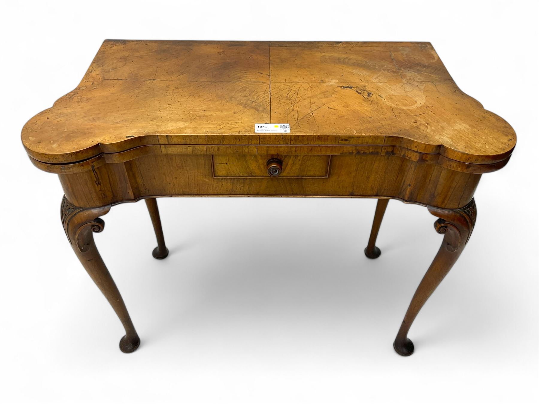 Georgian walnut fold-over card table, shaped rectangular top opening to reveal a baize-lined surface, supported by a concertina pull-out rear mechanism, frieze fitted with single drawer, raised on cabriole supports with foliate carvings terminating in pad feet