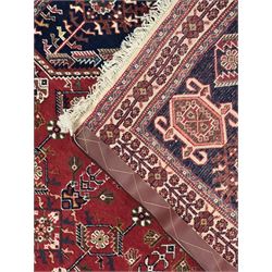 Persian Qashqai crimson ground runner, the central field decorated with three large geometric medallions with intricate angular and floral motifs, the indigo spandrels with complementary geometric designs, bordered by an ivory band with repeating floral patterns and angular vines