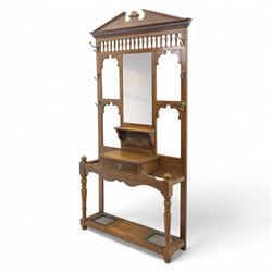 Edwardian walnut hall stand, the shaped pediment above turned spindle gallery and bevelled mirror, fitted with brass double coat hooks, single drawer with cast handle and carved frieze, flanked by turned supports, lower platform fitted with twin metal drip trays