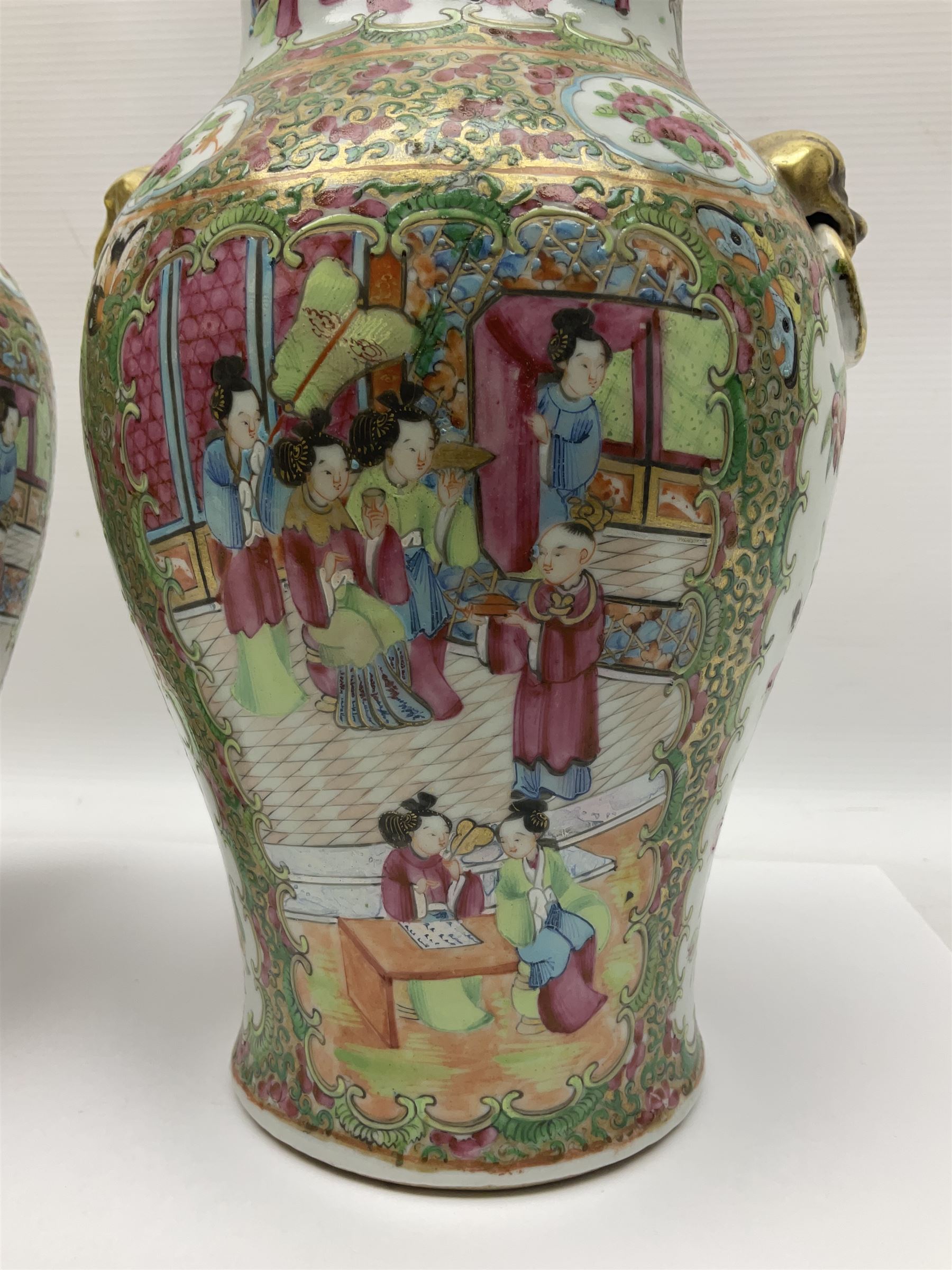 Pair of 19th century Chinese Famille Rose vases and covers, each of baluster form with twin gilt lion mask ring handles to shoulders, the flattened domed covers with gilt temple lion finials, each decorated with alternating reserves of bijin and attendants, and birds and butterflies amongst blossoming peonies, against a gilt ground profusely decorated with stylised scrolls, H32.5cm