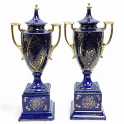 Pair of Vienna style blue porcelain two handled vases and covers painted with classical scenes on a dark blue and gilt ground and square socles, blue beehive mark H35cm