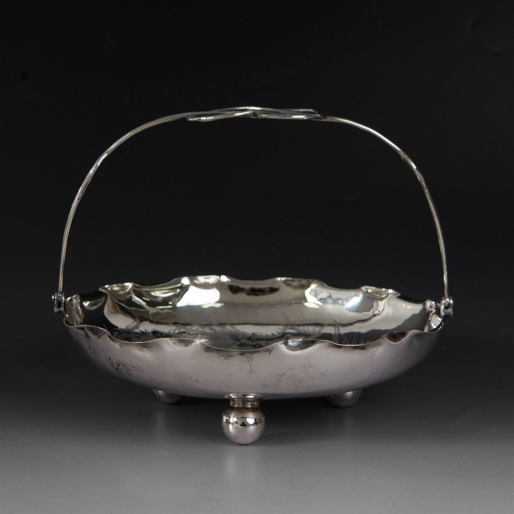 Chinese export silver swing handled basket, of circular for with crimped rim and knotted wirework handle, engraved with a dragon to centre, upon three bun feet, with maker's mark T.H, character marks and 95 to underside, including handle H17cm