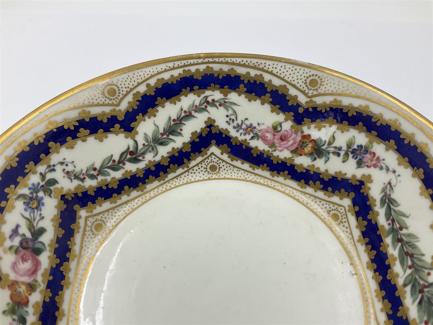 Sèvres soft paste porcelain coffee can and saucer with date code for 1767, painted with floral and laurel leaf garlands within blue scalloped and gilt borders, interlaced LL monogram enclosing the date letter O above painters mark for Catrice, coffee can H7.5cm, saucer D15cm
