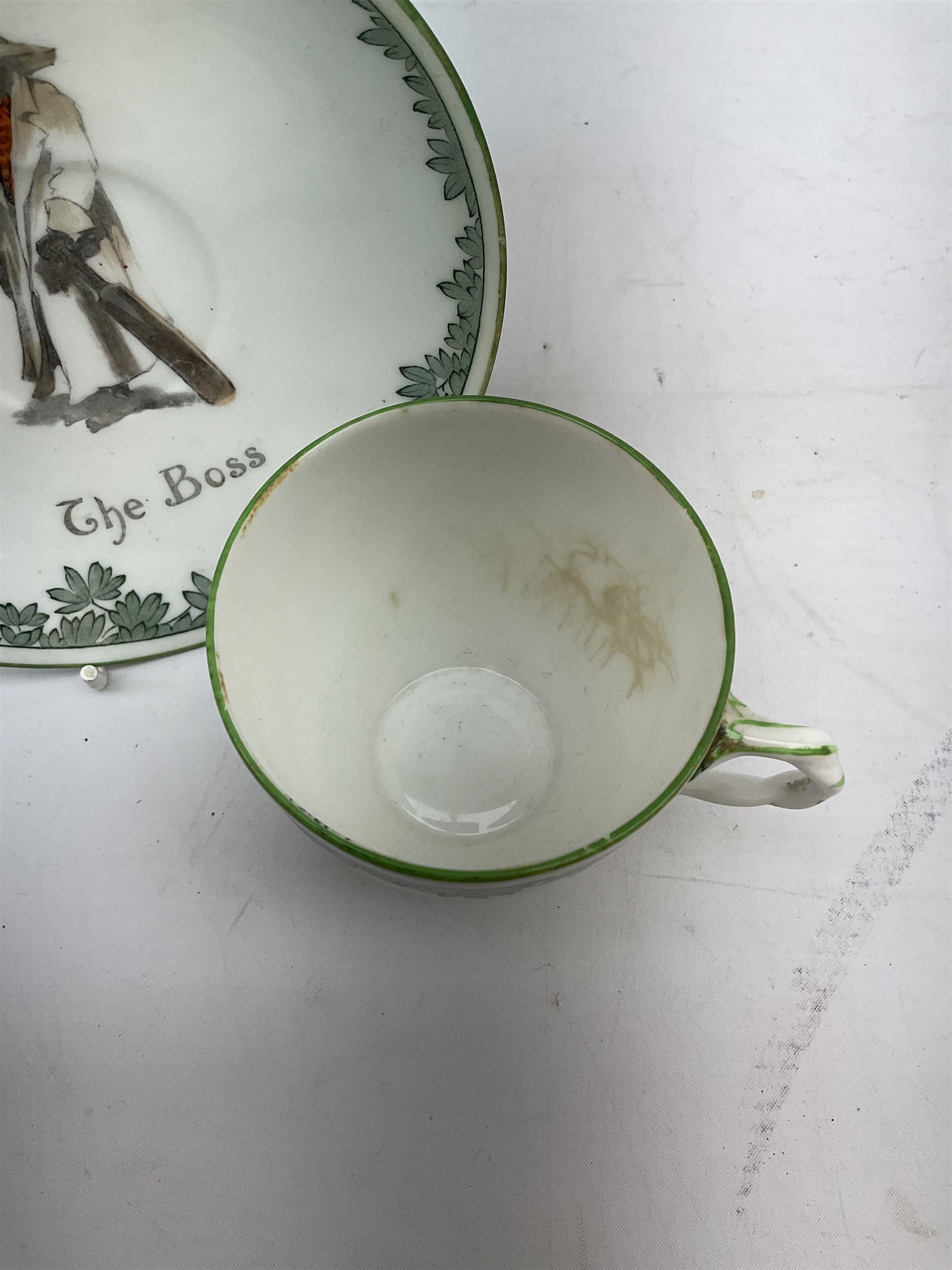 Early 20th century Royal Doulton teacup and saucer, from the series 'The All Black Team', the teacup depicting a cricketer entitled 'Good for fifty', the saucer depicting a cricketer stood in a long coat and wide brimmed hat, entitled 'The Boss', both with printed mark beneath, cup H6.5cm