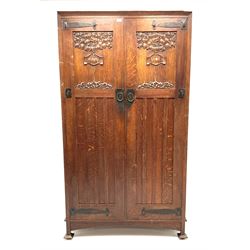 Shapland and Petter of Barnstaple - Arts & Craft style oak heavily carved wardrobe, double door enclosing fitted interior, stile supports, the locks stamped 'S.P.B'